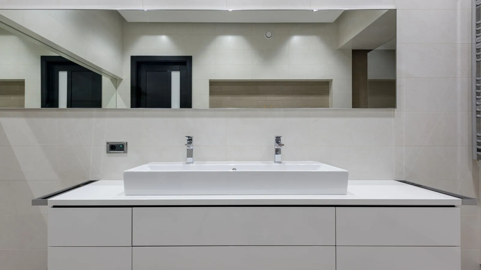 Salle de bain moderne avec meuble double vasque en bois, miroir rétroéclairé et carrelage gris clair