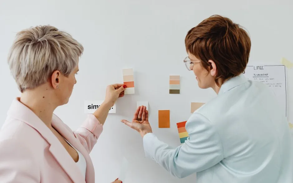 Deux personnes comparant des nuanciers de peinture devant un mur en cours de relooking