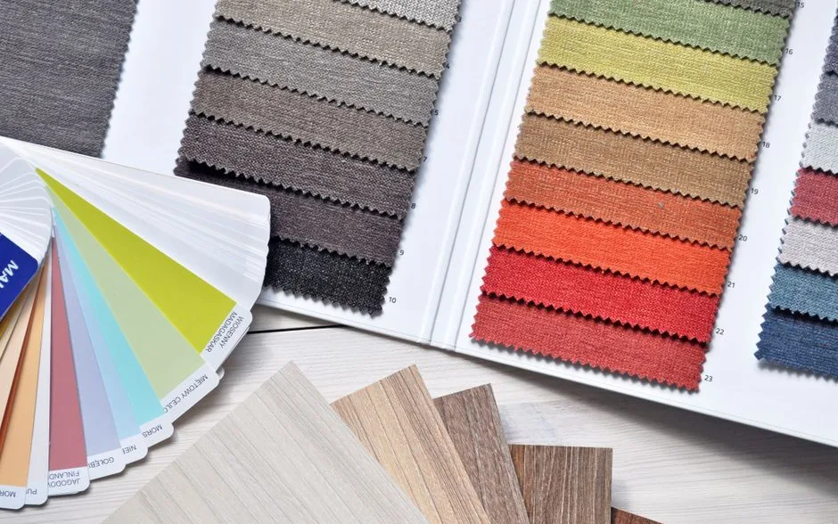 Nuanciers de peinture, rouleaux et échantillons de tissu étalés sur une table de travail