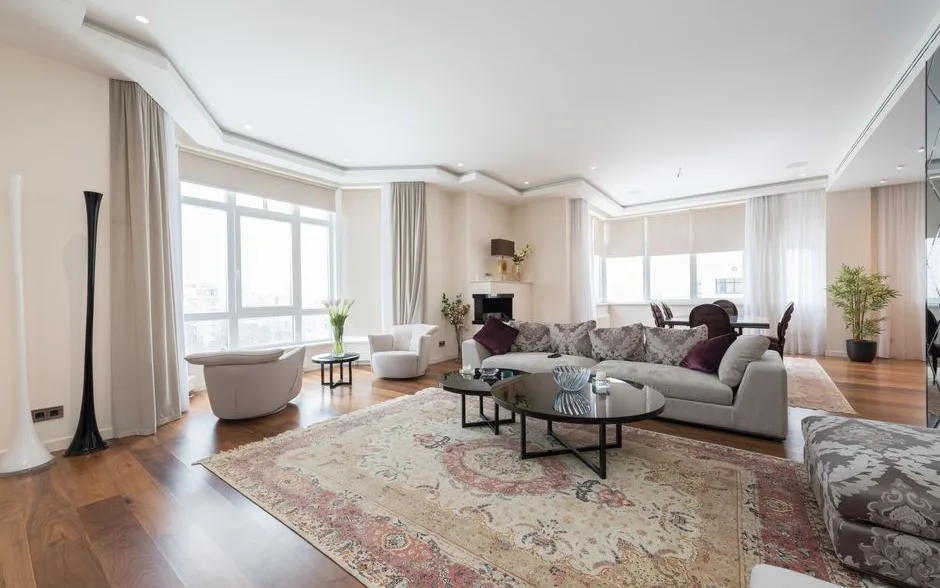 Salon avec un grand tapis clair glissé sous les pieds du canapé et une table basse ovale