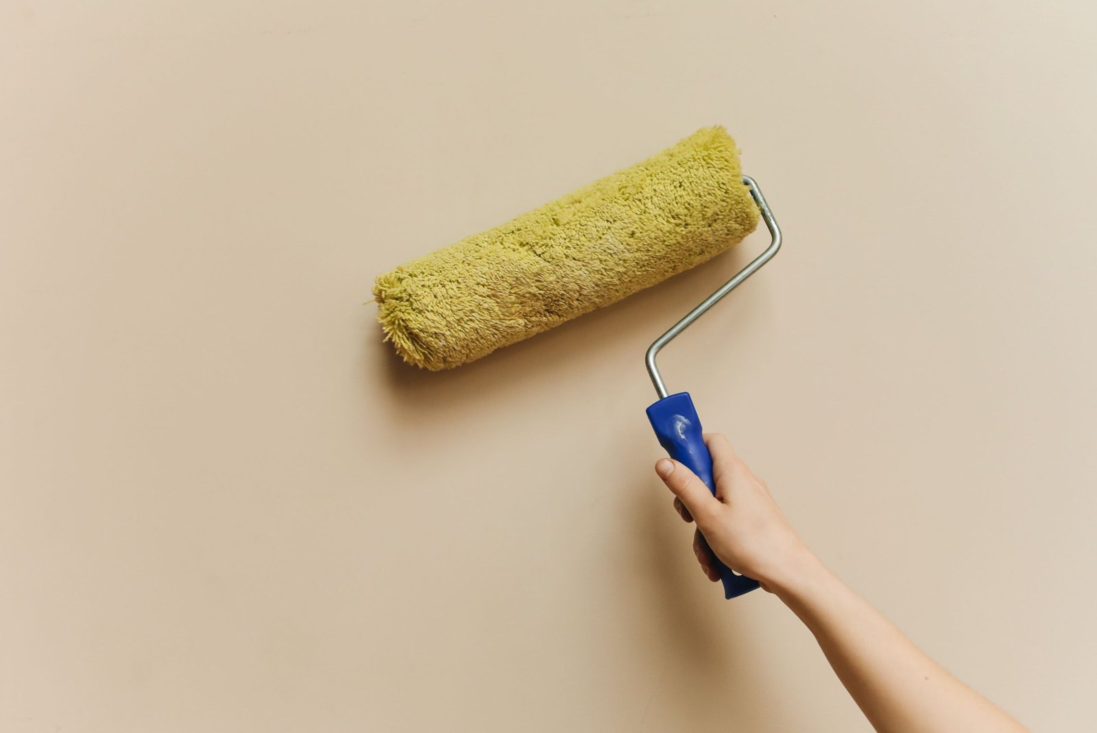 Un peintre applique une peinture airless sur un mur intérieur, pistolet en main, dans un salon en rénovation.
