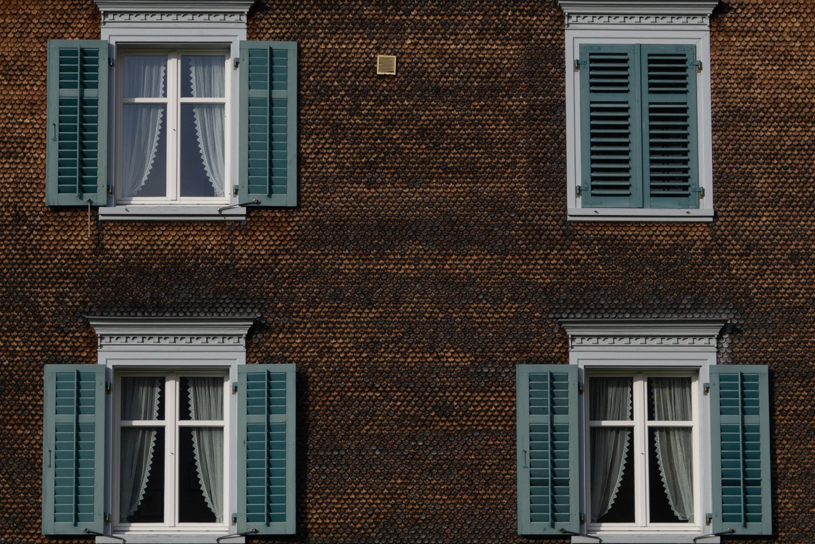 Un peintre applique une peinture airless sur un mur intérieur, pistolet en main, dans un salon en rénovation.